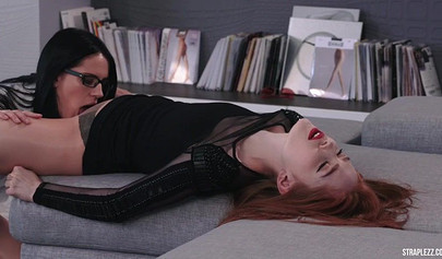 Redhead lesbo is joined by her friend in a strapless dildo fucking session