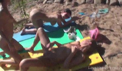 Outdoor lesbian foursome on a nude beach under the sun
