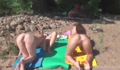 Outdoor lesbian foursome on a nude beach under the sun
