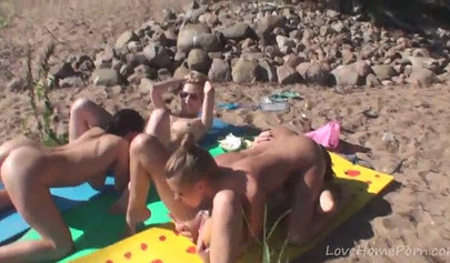 Outdoor lesbian foursome on a nude beach under the sun