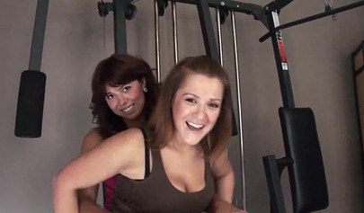Sweet lesbians play with a strap-on in the gym