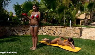 Tanned lesbians in bikinis are making love outdoors