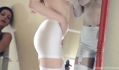 Lingerie-clad lesbians enjoy strapon sex in front of the mirror