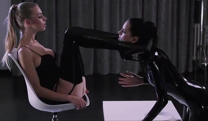 Eine in Latex gekleidete Lesbe vögelt eine heiße Blondine mit einem Strap-On.