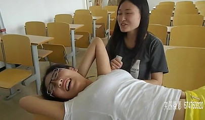 Chinese girls tickle each other in the classroom
