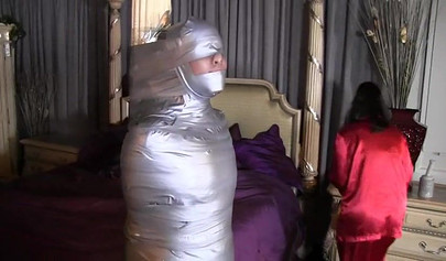 Two mature ladies enjoy a mummification fetish in the bedroom
