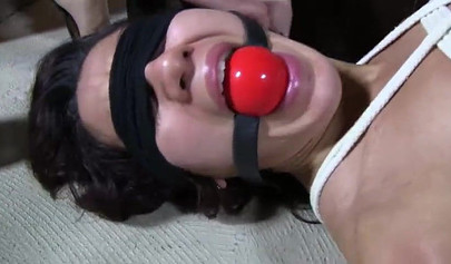 Vídeo de bondage BDSM con una morena con los ojos vendados, amordazada y atada.